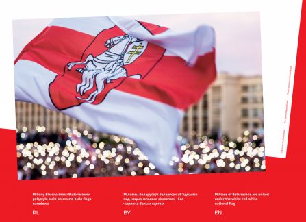Fotografia z wystawy Białoruś. droga do wolności. biało-czerwono-biała flaga narodowa białorusi z herbem. w tle nieostre zarysy protestującego tłumu, jasne punkty świateł.